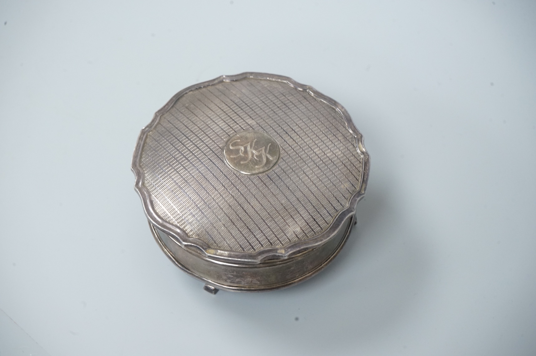 A George V silver mounted trinket box, by Adie Brothers, Birmingham, 1924, diameter 89mm. and a chrome magnifying glass, later added to a knife handle, handle by Goldsmiths & Silversmiths Co Ltd, London, 1894, 21.7cm.